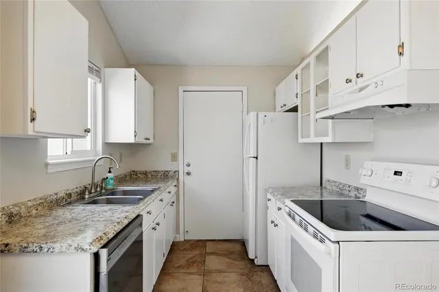 a kitchen with granite countertop a sink a stove and refrigerator