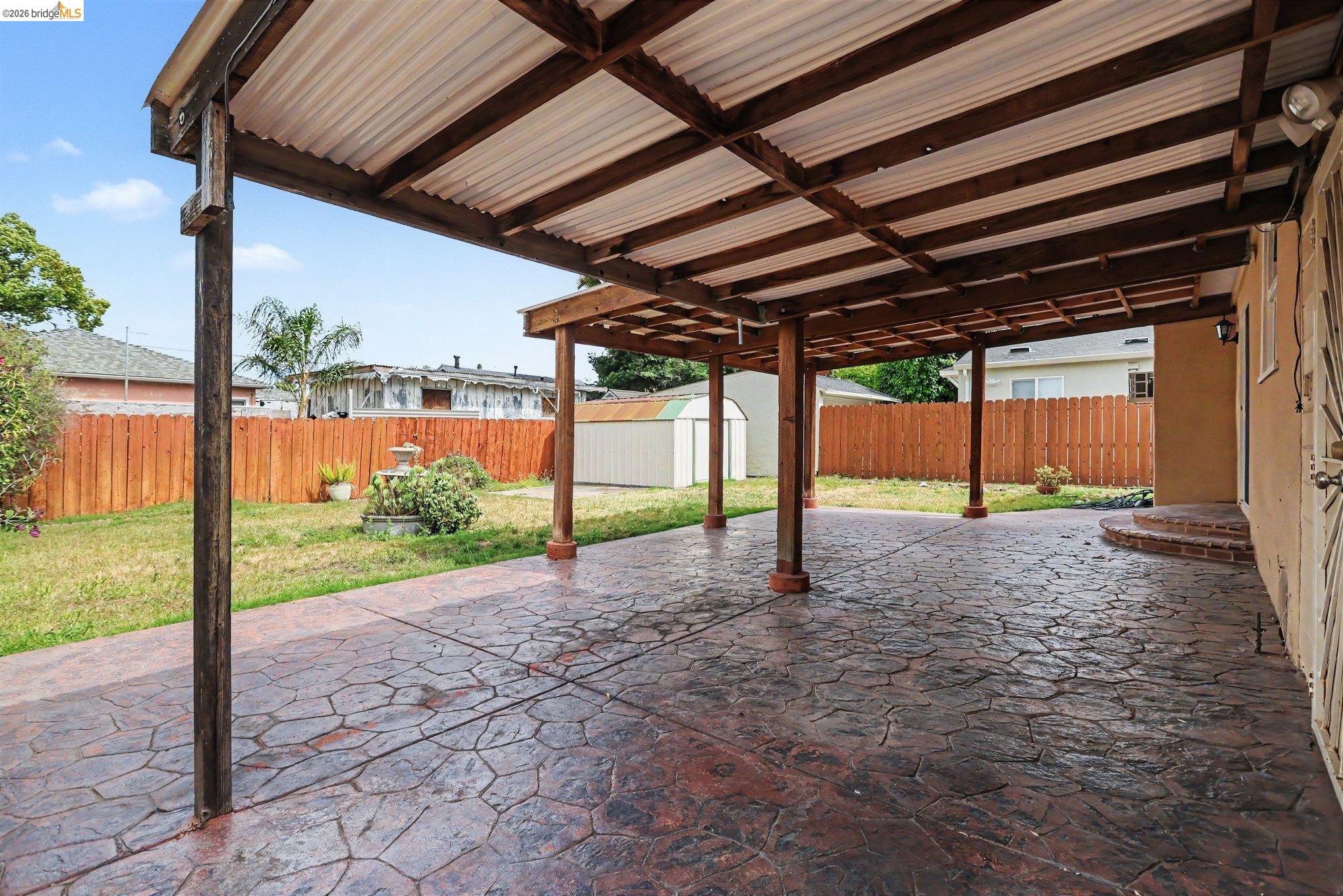 249 Madison Avenue Bay Point, CA 94565 - Photo 12 of 18 Expansive covered patio featuring stamped concrete flooring, exposed wood beams, and a corrugated roof