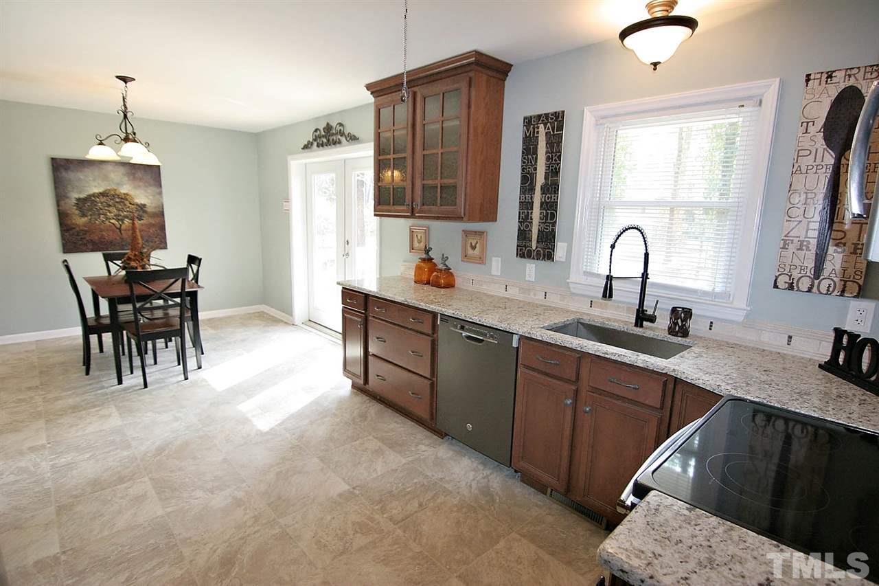 3404 Victor Place Raleigh, NC 27604 - Photo 8 of 22 a kitchen with stainless steel appliances kitchen island granite countertop a sink dishwasher a dining table and chairs with wooden floor