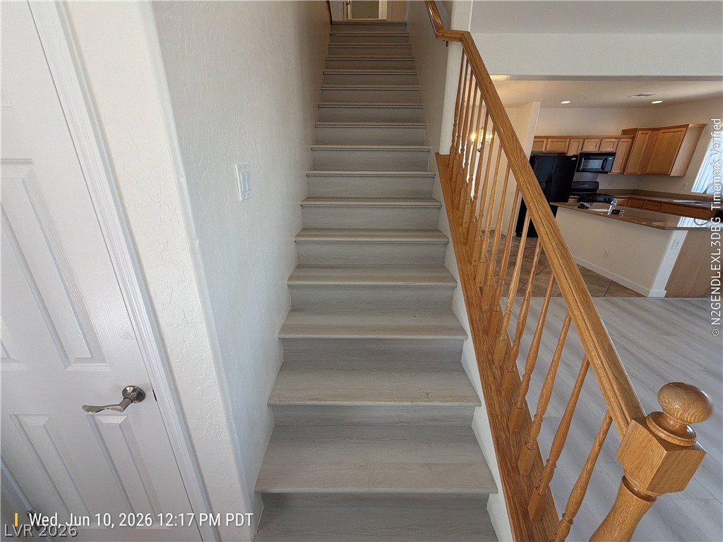 2388 Rue Bienville Way Henderson, NV 89044 - Photo 8 of 16 A grand staircase with natural wood railings leads to a bright, open-concept living area.
