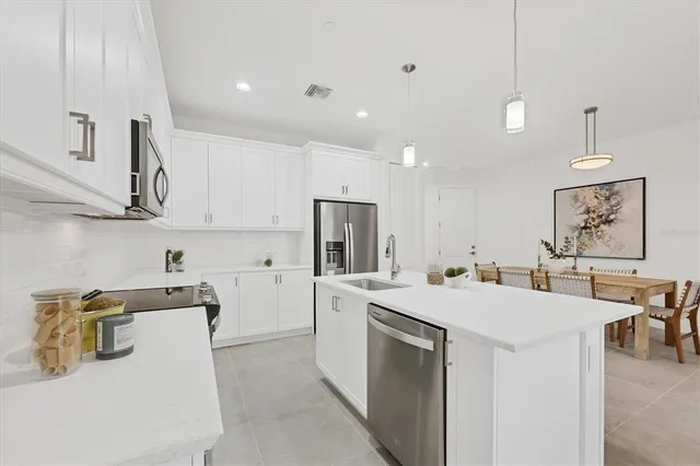 a view of a kitchen with kitchen island a sink stainless steel appliances and cabinets