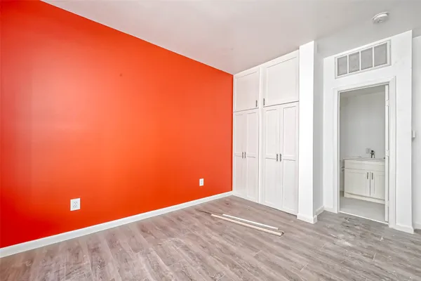 a view of empty room with wooden floor and bathroom