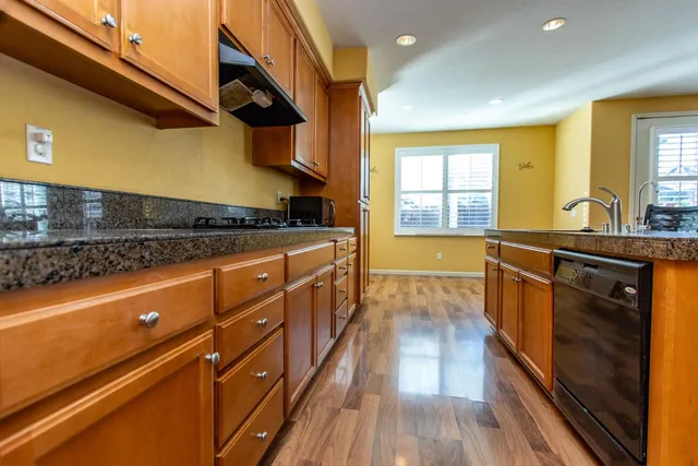 a kitchen with stainless steel appliances granite countertop wooden floors a refrigerator and cabinets