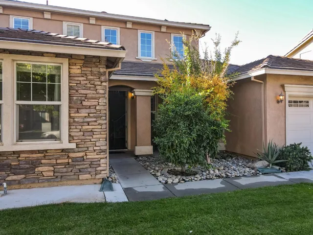 a view of a brick house with a yard and plants