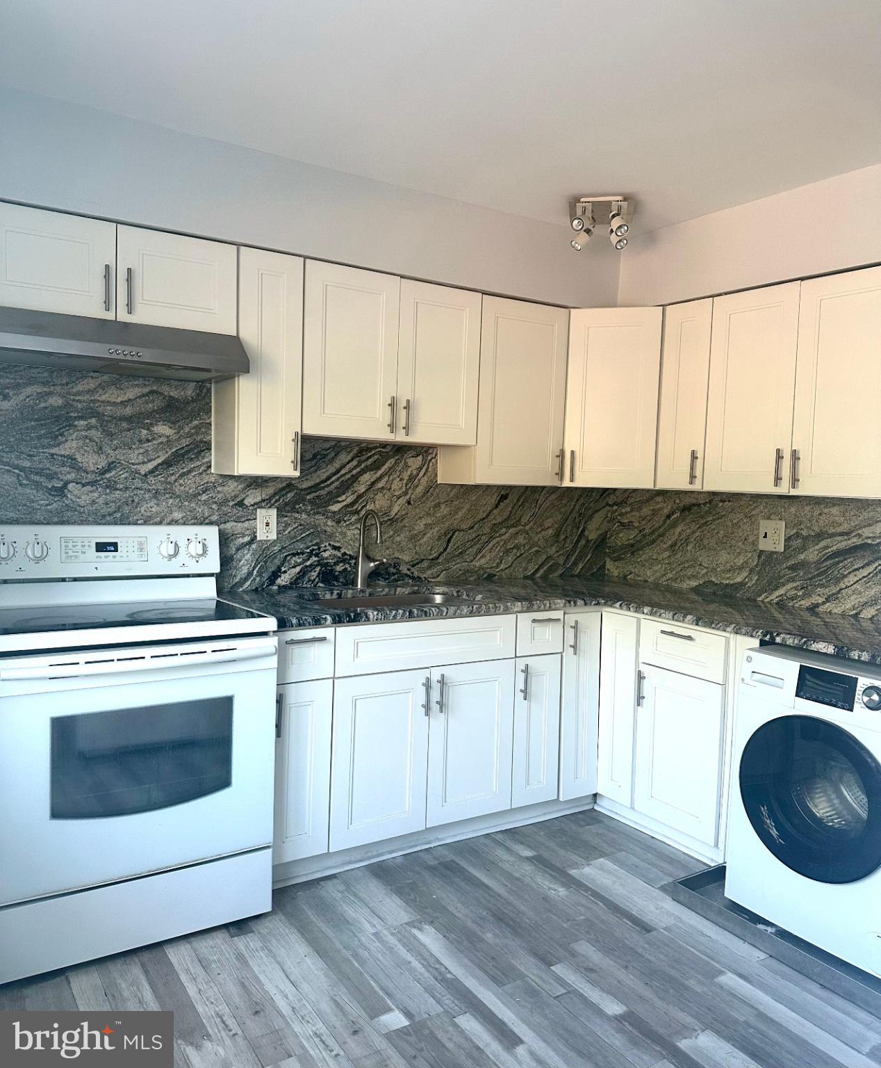 a kitchen with granite countertop a stove a sink and a microwave