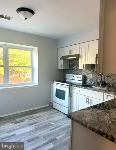 a kitchen with granite countertop a stove a sink and a microwave