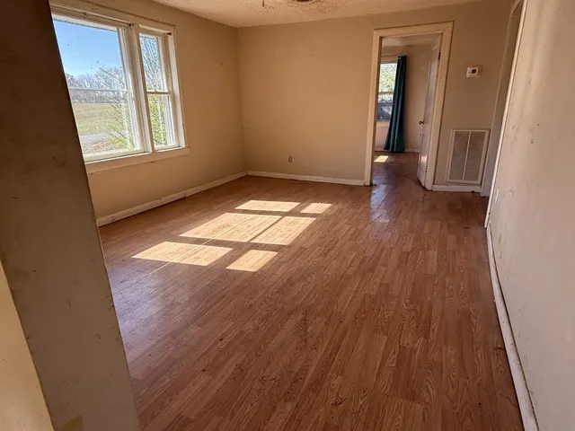 an empty room with wooden floor and windows