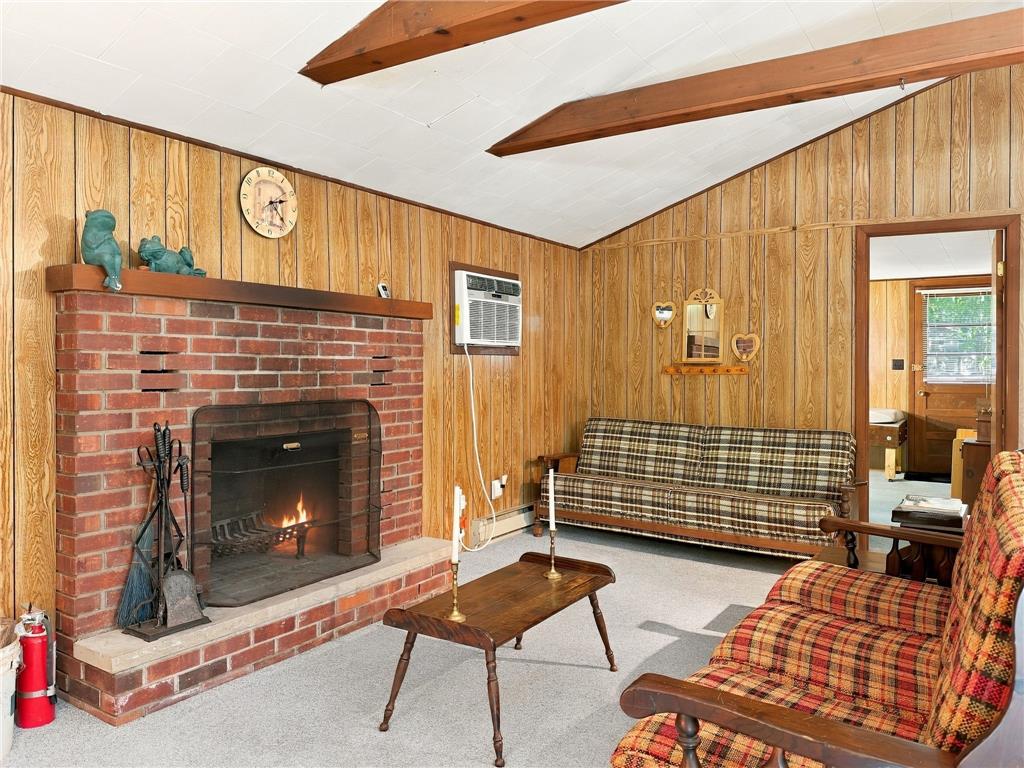 116 Aspen Road Albrightsville, PA 18210 - Photo 18 of 33 Rustic wood paneling and exposed ceiling beams frame a classic brick fireplace.