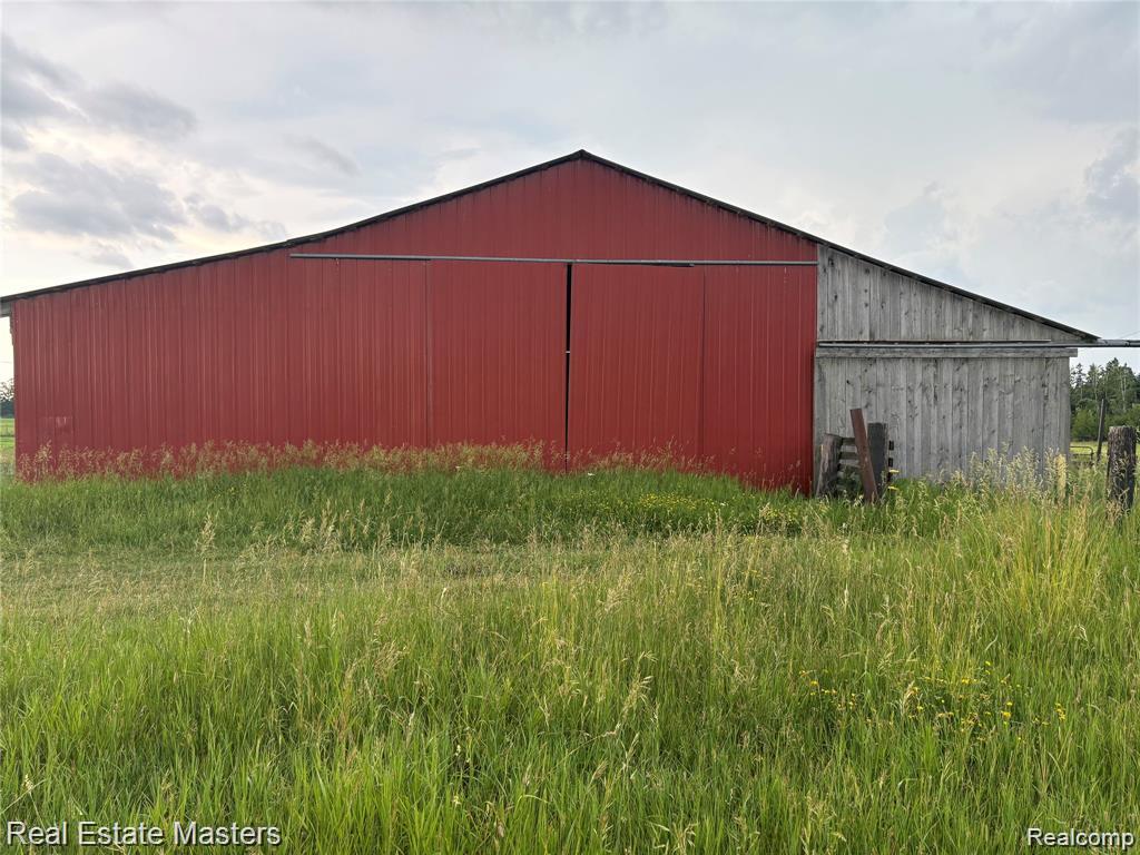 300 East Hubert Road Hubbard Lake, MI 49747 - Photo 1 of 9 Metal-sided barn featuring a red facade and gray wood-sided extension