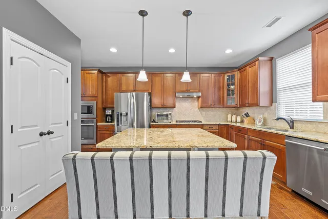 a kitchen with stainless steel appliances granite countertop a sink a stove and a wooden floors