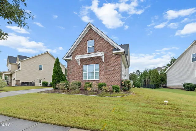 a front view of house with yard and trees in the background