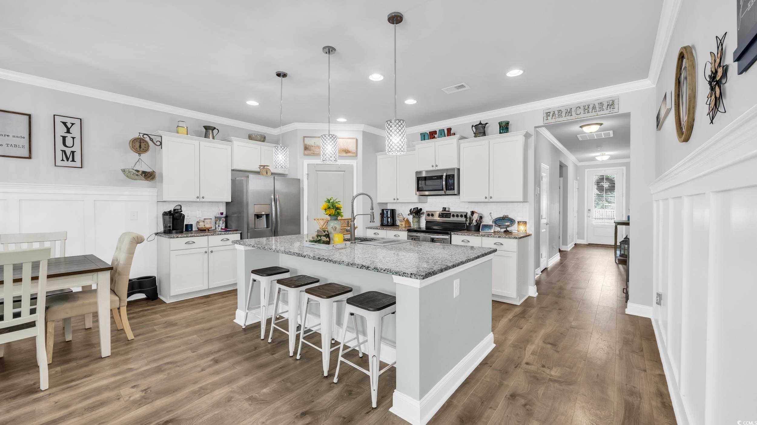 1102 Inlet View Drive North Myrtle Beach, SC 29582 - Photo 2 of 33 Kitchen with a kitchen bar, white cabinets, ornamental molding, a center island with sink, and appliances with stainless steel finishes