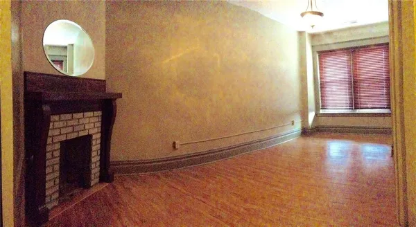 a view of an empty room with wooden floor and closet