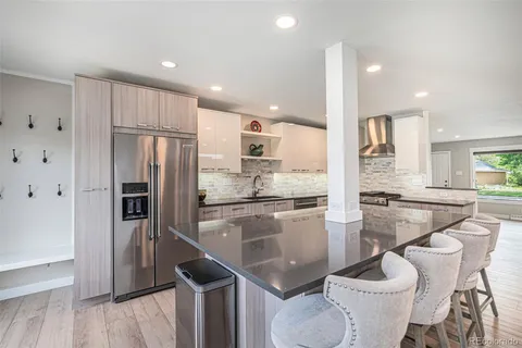 a kitchen with stainless steel appliances granite countertop a stove top oven a sink dishwasher a dining table and chairs with wooden floor