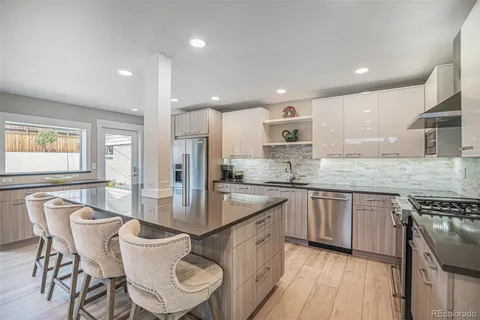 a large kitchen with stainless steel appliances granite countertop a stove top oven a sink dishwasher a dining table and chairs with wooden floor