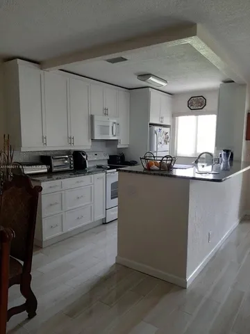 a kitchen with stainless steel appliances granite countertop a sink a stove a refrigerator a center island and cabinets