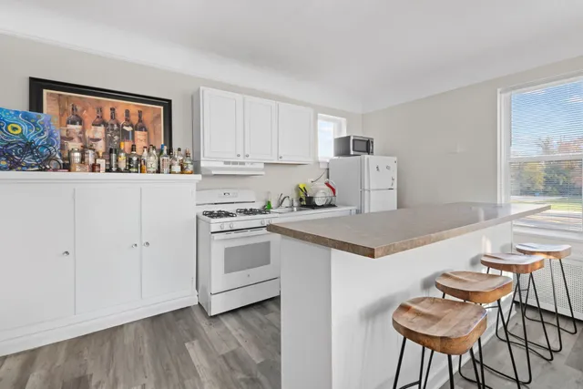 a kitchen with stainless steel appliances granite countertop a stove a refrigerator and white cabinets with wooden floor