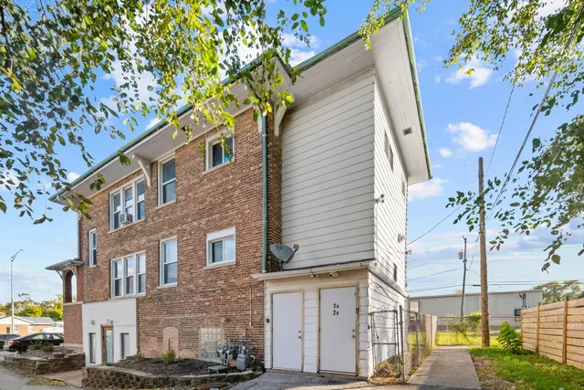 a view of a brick building next to a road with large trees