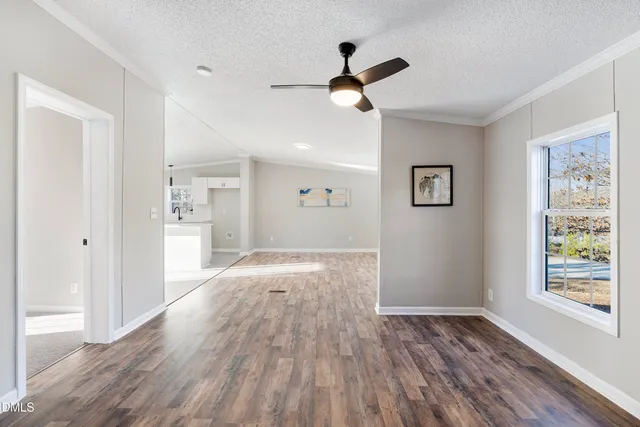 a view of empty room with wooden floor and fan