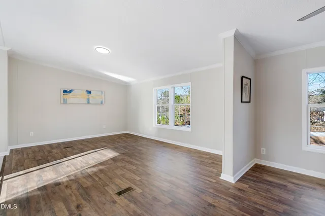 a view of empty room with wooden floor and window
