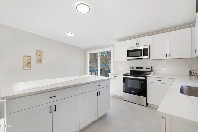a kitchen with granite countertop white cabinets and stainless steel appliances