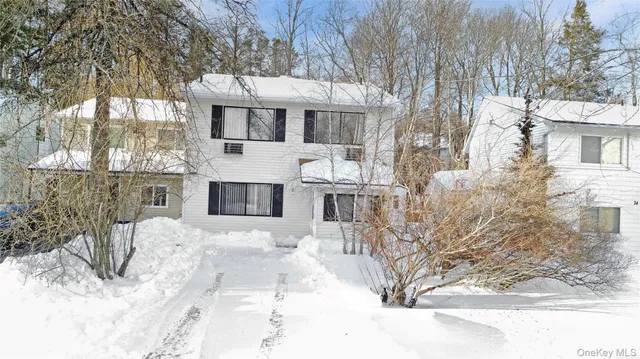 a view of a white house next to a yard with large trees