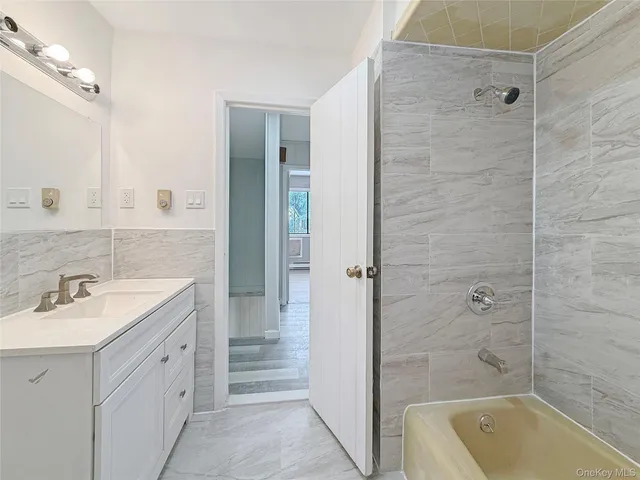 a bathroom with a granite countertop bathtub shower sink vanity and mirror