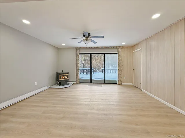 an empty room with chandelier fan and windows
