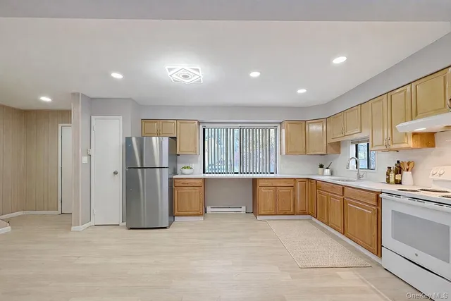 a large kitchen with a refrigerator and white cabinets