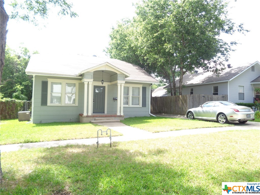 a front view of a house with a garden and trees