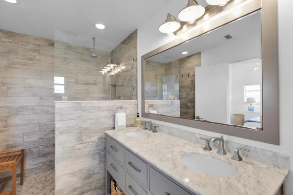 a bathroom with a granite countertop sink a large mirror and a shower