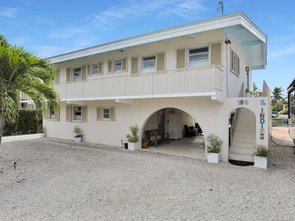 a view of a house with a barbeque and large trees