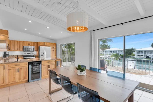 a open dining room with stainless steel appliances granite countertop a stove top oven a dining table and chairs with wooden floor