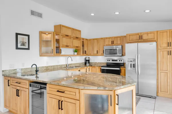 a kitchen with kitchen island granite countertop a sink stainless steel appliances and cabinets