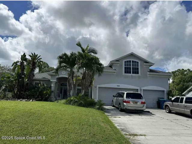 a white house with a big yard and large trees