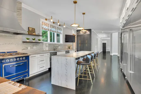 a kitchen with stainless steel appliances kitchen island granite countertop a stove a sink and a refrigerator