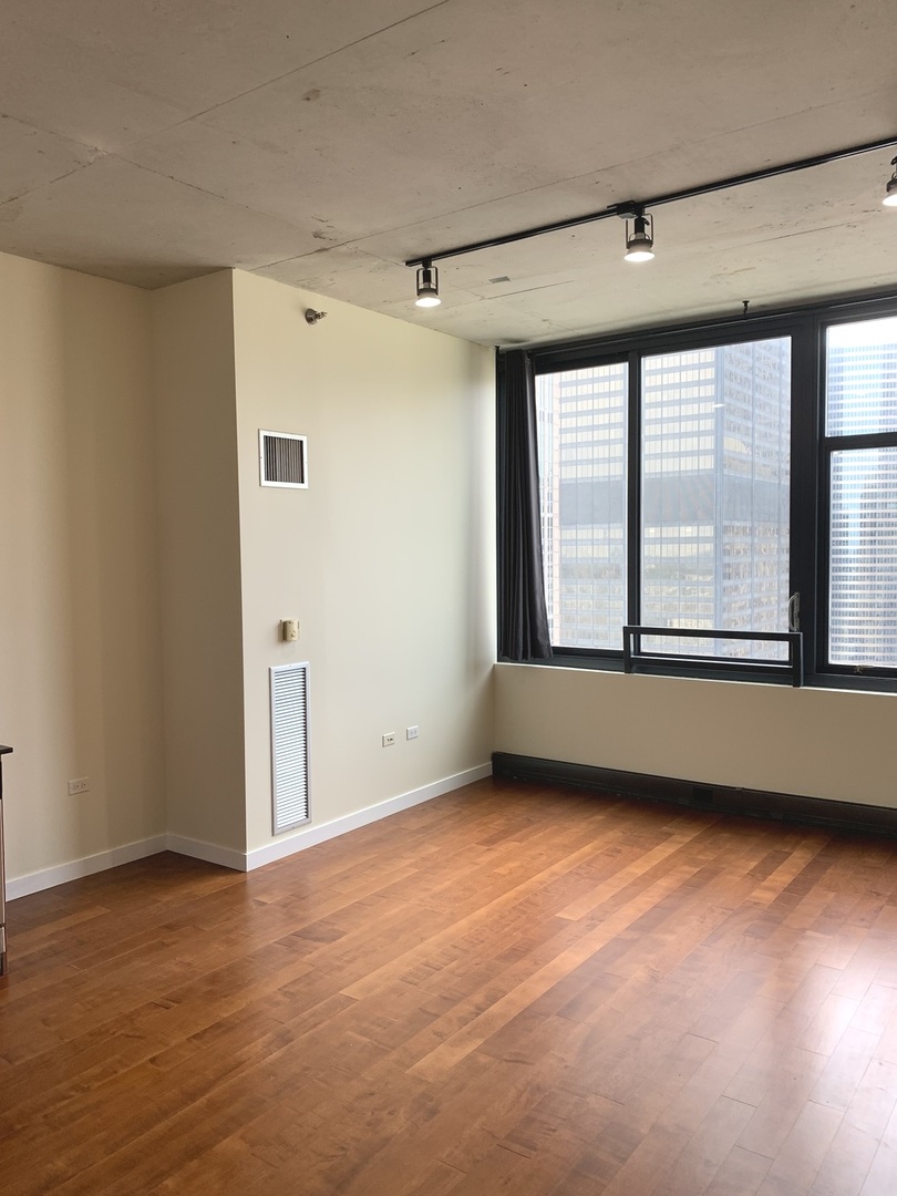 235 West Van Buren Street, Unit 3820 Chicago, IL 60607 - Photo 11 of 38 a view of an empty room with a window and wooden floor