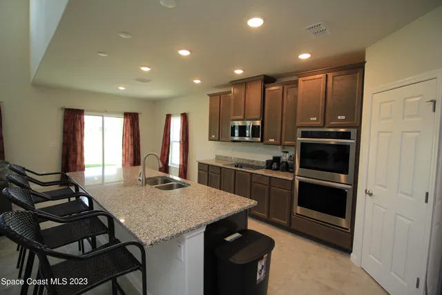 a kitchen with stainless steel appliances kitchen island granite countertop a stove a sink dishwasher and a refrigerator with wooden floor