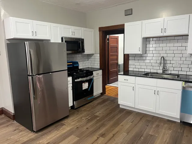 a kitchen with granite countertop stainless steel appliances a refrigerator a sink a stove and cabinets