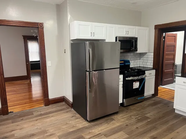 a kitchen with a refrigerator stove and wooden floor