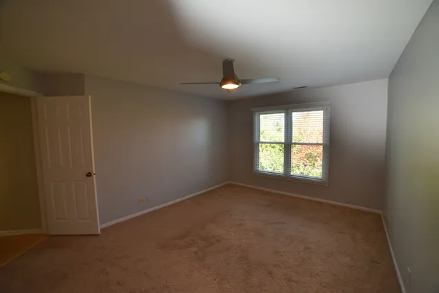 an empty room with a ceiling fan and a window