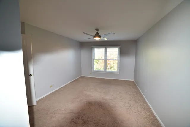 an empty room with a window and a fan