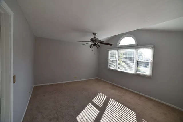 an empty room with ceiling fan and windows