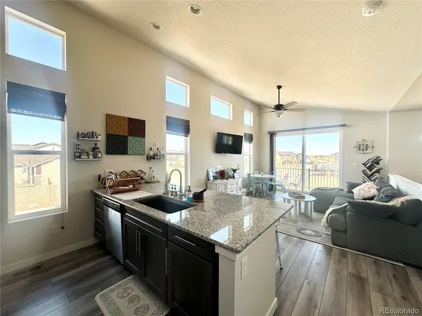 a open kitchen with stainless steel appliances granite countertop a stove top oven a sink dishwasher a dining table and chairs with wooden floor