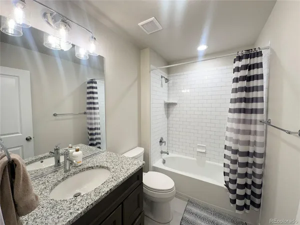 a bathroom with a granite countertop sink toilet mirror and shower