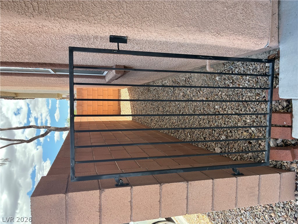 7727 Pista Way Las Vegas, NV 89179 - Photo 11 of 12 Secure iron gate providing controlled entry along a textured exterior wall.
