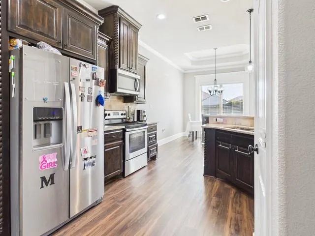 a kitchen with stainless steel appliances granite countertop a refrigerator a stove and a wooden floors