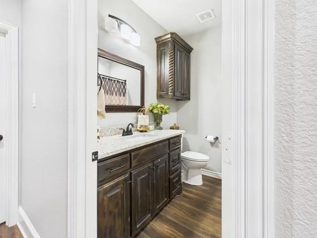 a view of a hallway with wooden floor and a bathroom