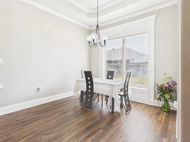 a dining room with furniture wooden floor a potted plant and a chandelier