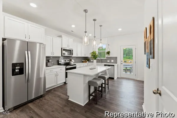 a kitchen with stainless steel appliances a refrigerator a stove a sink dishwasher a oven with white cabinets and wooden floor